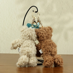 Detail of plush teddy bear keychains in cream and brown with gold metal lobster clasps