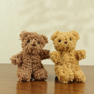 Detailed view of brown and tan teddy bear plush keychains on a warm wooden surface