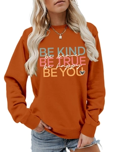 Detail of orange crewneck sweatshirt featuring Be Kind inspirational text and leopard heart
