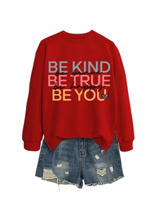 Flat lay of red sweatshirt with Be Kind text and distressed blue denim shorts combo