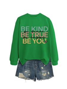 Detail of green crewneck sweatshirt featuring colorful inspirational slogans and leopard heart