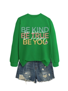 Detail of green crewneck sweatshirt with colorful slogans and distressed denim shorts