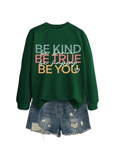 Detail of dark green sweatshirt with Be Kind Be Brave prints and ripped denim shorts