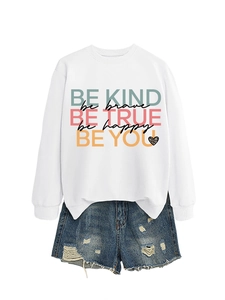 Detail of Be Kind Be Brave graphic print on white sweatshirt with denim shorts