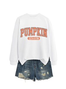 Gros plan de l'imprimé Pumpkin Season sur sweat blanc avec short en jean usé