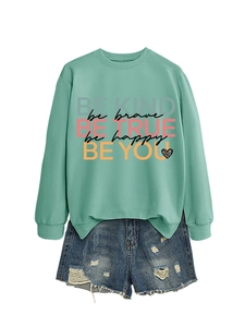 Detail of mint green sweatshirt with 'be kind' slogans paired with distressed denim shorts