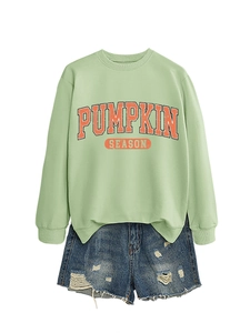 Gros plan du motif Pumpkin Season sur sweat vert menthe avec short en jean usé