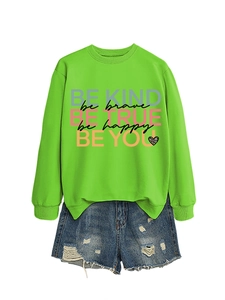 Detail of green sweatshirt with 'BE KIND' print and distressed denim shorts set