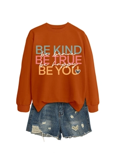 Detail of caramel sweatshirt with BE KIND colorful print and distressed denim shorts