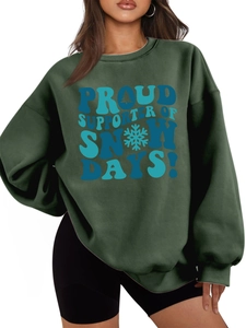 Detail of ribbed cuffs and snowflake graphic print on warm dark green crewneck sweatshirt