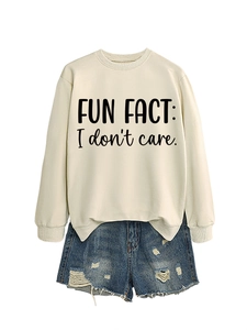 Detailed view of cream sweatshirt with 'FUN FACT: I don't care.' text and denim shorts