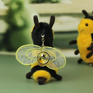 Detailed view of plush bee charm featuring embroidered mesh wings and golden hardware