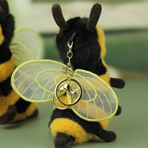 Detailed shot of plush bee charm featuring gold-embroidered mesh wings and metal clasp