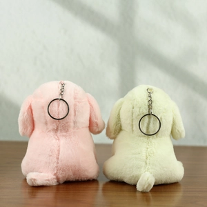 Dettaglio di portachiavi a forma di cane in peluche rosa e beige con anelli neri