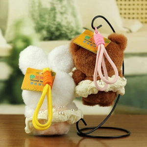 Detail of plush bear and rabbit charms featuring lace dresses with pearl accents and braided ropes