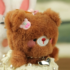 Macro detail of brown plush bear pendant with pink cherry patch and pearl charm
