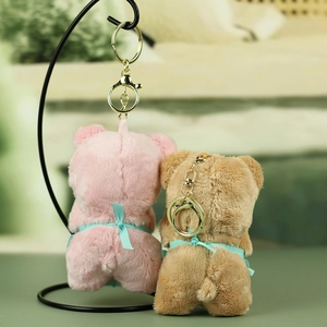 Detailed view of pink and brown plush bear keychains with decorative green ribbons