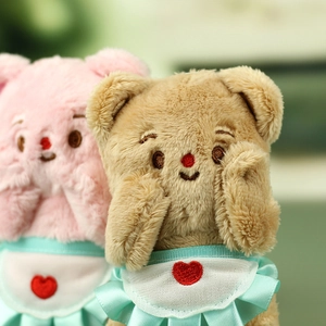 Macro detail of plush bears in pink and brown with mint green aprons and heart embroidery