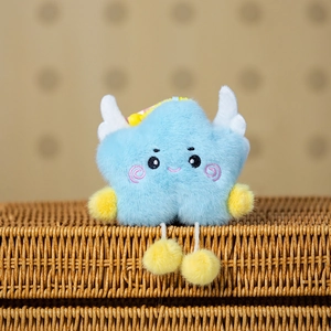 Close-up of a blue plush cloud charm with white wings and yellow pompoms on a basket