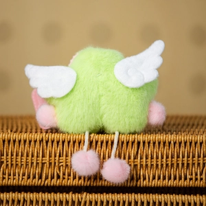 Close-up of a plush star charm with white wings and pink pom-poms on a woven basket