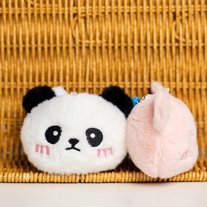Primer plano de llaveros de peluche de panda y cerdito con bordado sobre una cesta
