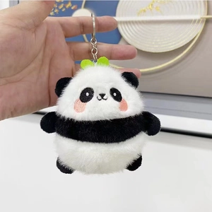 Close-up of cute panda plush keychain with green leaf held by hand for bag decoration