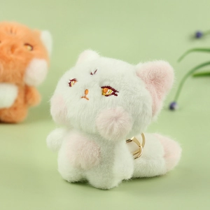 Close-up of white plush fox keychain with soft pink accents and a gold metal ring