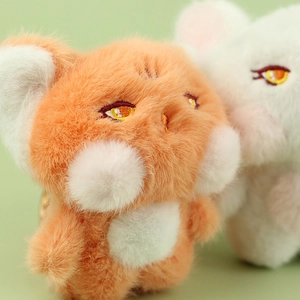 Close-up of cute plush fox pendants with soft orange fur and golden metal keyrings