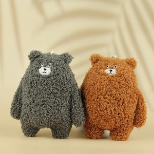 Cute plush bear keychains in brown and grey fleece with metal hooks on warm background