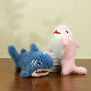 Set portachiavi in peluche a forma di squalo blu e rosa con ricami su sfondo legno