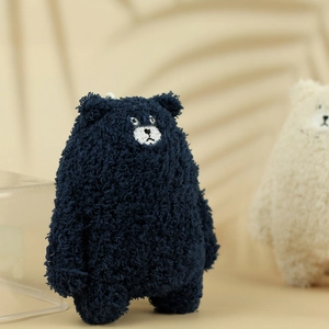 Detail shot of navy blue teddy fleece texture and hand-embroidered bear face on plush keychain