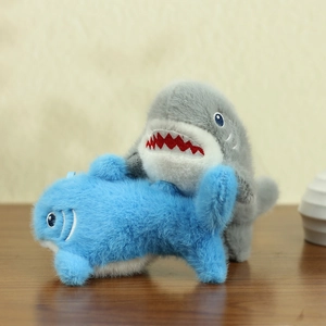Dettaglio ravvicinato di portachiavi a forma di squalo in peluche blu e grigio ricamato