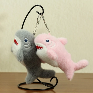 Dettaglio di portachiavi a squalo in peluche grigio e rosa con denti ricamati sul supporto