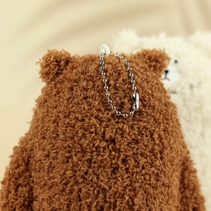 Detailed macro view of the curly plush brown bear charm with a silver ball chain fastener