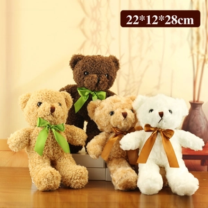 Three plush teddy bears with silk bows in brown and white on a wooden desk