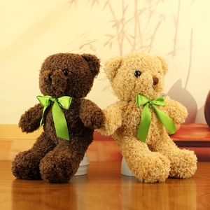 Plush teddy bears in dark brown and tan with bright green silk scarves on warm background