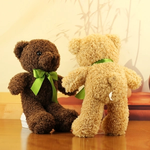 Detailed view of plush teddy bears in brown and cream colors with green silk bows