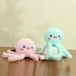 Cute plush octopus charms in pink and mint green colors on a wooden surface