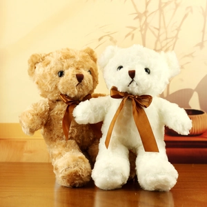 Detail of plush teddy bears in brown and white with satin bows on a warm wooden background