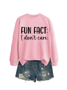 Close-up of pink crewneck sweatshirt with 'FUN FACT: I don't care' print and denim shorts