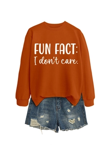 Detail of orange round neck sweatshirt with 'FUN FACT: I don't care' text and denim shorts