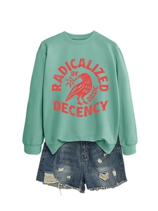 Détail du sweat vert menthe avec texte imprimé et short en jean bleu délavé à trous