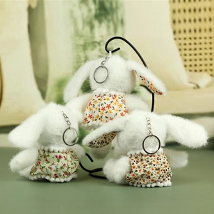 Detailed view of three plush bunny keychains wearing different floral dress patterns