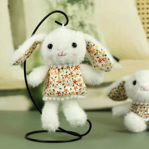 Detailed view of plush rabbit doll in floral dress hanging on a metal display stand