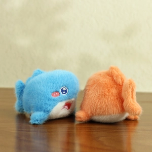 Close-up of cute blue and orange plush marine animal charms on a wooden background
