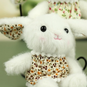 Close-up of white plush bunny doll with yellow floral dress and soft pink blush details