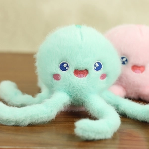 Close-up of a soft plush octopus toy with detailed embroidery and blue eyes on wood