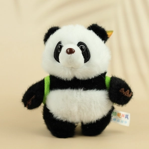 Schattige panda pluche sleutelhanger met groene rugzak op zachte stoffen ondergrond