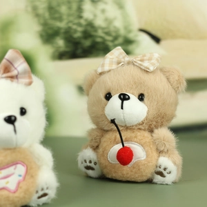 Détail d'un ours en peluche marron avec un nœud et un accessoire cerise