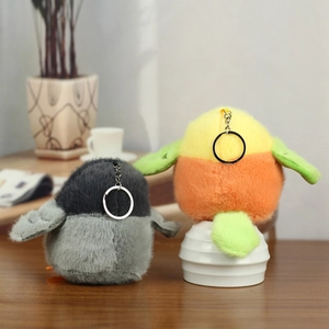 Cute plush penguin and sparrow bird keychain charms with metal rings on wooden table